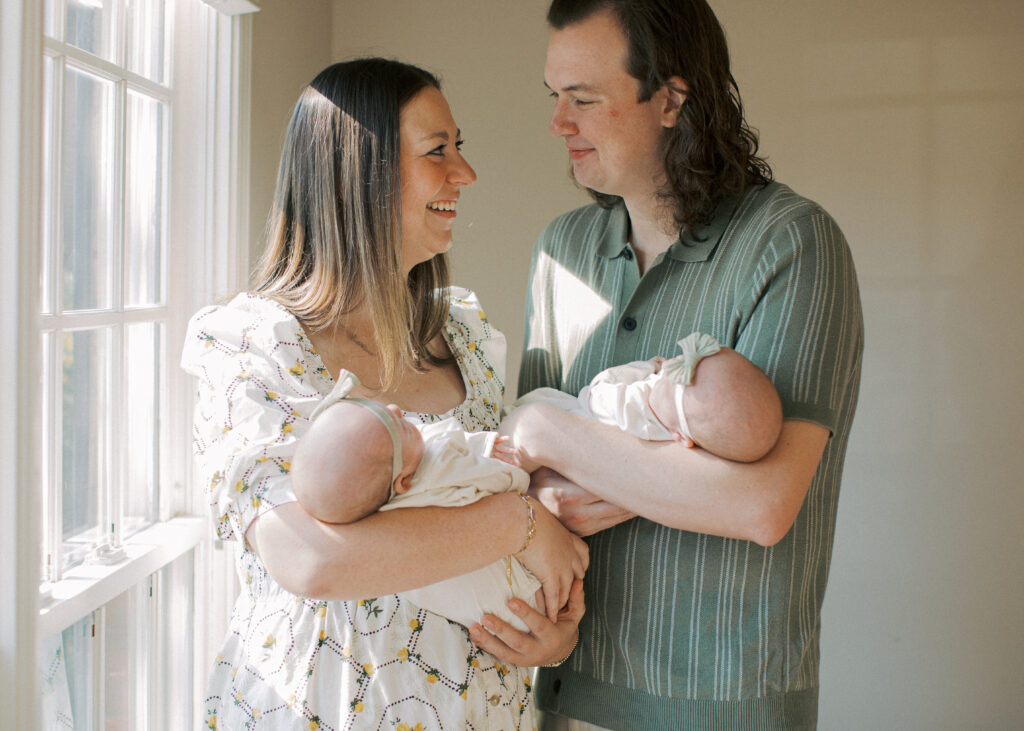 parents snuggling newborn twins and looking at each other